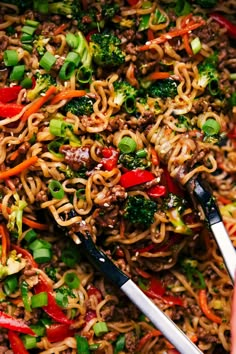 a close up of noodles with broccoli and peppers in a pan on the table