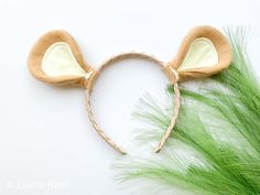 a close up of a mouse ears headband on a white surface with green grass