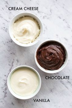 three bowls filled with different types of cream cheese and chocolate ice cream on top of a marble counter