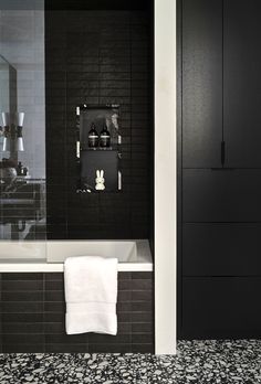 a bathroom with black and white tile walls, flooring and a bathtub in the corner