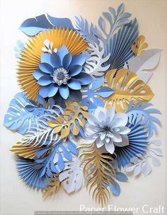 paper flowers are arranged on the wall in blue, yellow and white colors with leaves