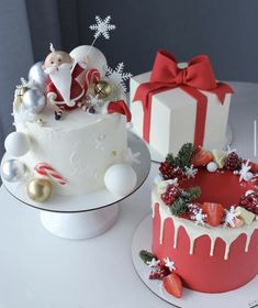 two cakes decorated with white frosting and red decorations on top of a table next to each other