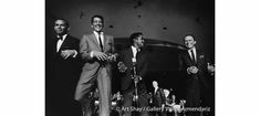 four men in suits and ties standing next to each other with microphones behind them