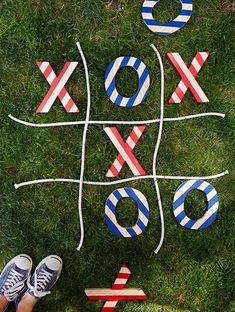 a person standing in the grass next to a tic - tac toe game