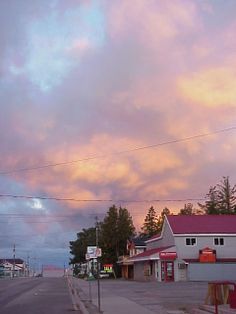 the sky is pink and purple as it sits over an empty street in front of some buildings