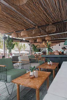 an outdoor restaurant with wooden tables and green chairs on the outside patio, along with hanging bamboo lamps