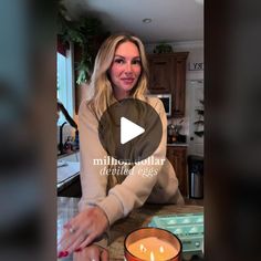 a woman sitting at a table with a candle in front of her on the counter