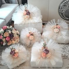 four white boxes with flowers on them are sitting on a table in front of a couch