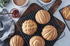 several baked goods sitting on top of a cooling rack next to cups and sauces