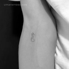 a black and white photo of a woman's stomach with a small snake tattoo on it