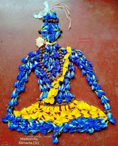 a person made out of blue, yellow and brown paper sitting in a yoga position