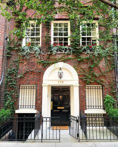 an old brick building with ivy growing all over it's walls and doors, along with wrought iron railings