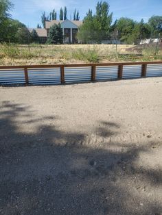 an empty parking lot in front of a fenced off area with trees and grass