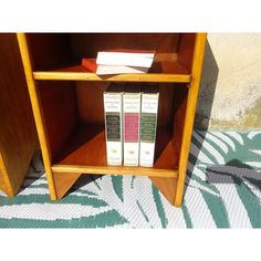 two books are sitting on top of a book shelf in front of a wallpapered floor