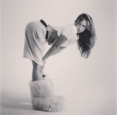 a woman in white shirt and furry boots posing for a black and white photo with long hair