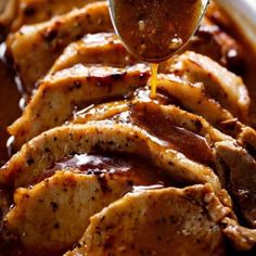 a spoon drizzling sauce on top of sliced pork in gravy