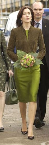 two women in green dresses walking down the street with one holding a purse and another carrying a handbag