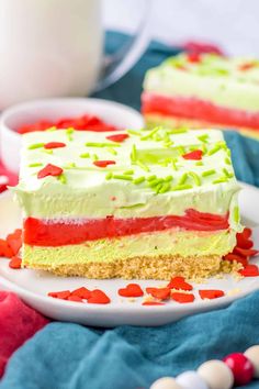 a piece of cake on a plate with red and green frosting next to a glass of milk