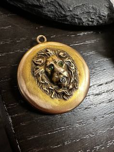 "A 10k gold repousse jeweled Lion head Locket-Fierce.  Condition is very good for its age, any wear slight and commensurate with age-photos show the details.  Size approx. 1\" in diameter, wt.- 4.4 grams, hinge is good, closes tight, old cut Diamond in mouth with green stone eyes.  This king of the Jungle rocks.  Circa 1910 American, tests for 10k gold, monogramed on back.  A treasure to behold." Gold Engraved Emerald Jewelry, Gold Emerald Jewelry With Engraving, Engraved Gold Emerald Jewelry, Engraved Emerald Gold Jewelry, Victorian Green Medallion Jewelry, Green Medallion Locket Jewelry, Green Locket Jewelry, Collectible Yellow Gold Necklace With Antique Finish, Bronze Locket Pendant Jewelry