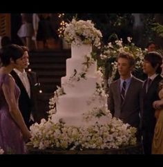 a group of people standing around a wedding cake