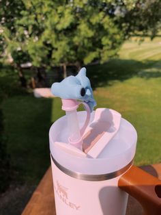 a pink and white blender sitting on top of a wooden table next to a tree