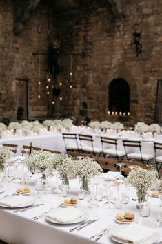 the tables are set with white flowers and place settings