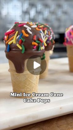 three ice cream cones with chocolate frosting and sprinkles are on a tray