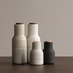 three white and black vases sitting on top of a wooden table next to each other