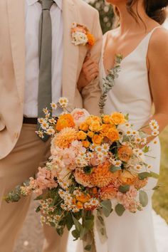 A Bride Holding Her Bridal Bouquet Thats Filled With Orange, Whites, And Greens. Peach Fall Wedding, Wedding Bouquets Orange, Bright Orange Wedding, Fall Wedding Bridal Bouquets, Flower Table Centerpieces, Diy Wedding Bouquet Tutorial, Whimsical Fall Wedding, Peach Wedding Flowers, Fall Wedding Color Palette