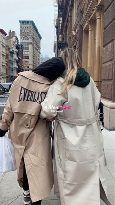 two people are walking down the street with their backs to each other and one person is carrying shopping bags