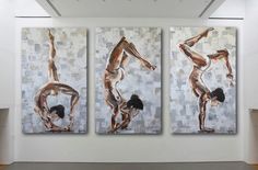 three paintings are hanging on the wall in an art gallery, one has a woman doing a handstand