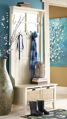 a room with blue walls and a vase filled with flowers next to a white bench