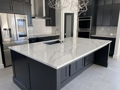 a large kitchen with an island and stainless steel appliances in the center, surrounded by black cabinets