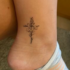 a woman's foot with a cross and flower tattoo on the side of her leg