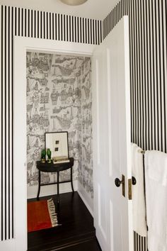 a hallway with black and white wallpaper, striped walls and a small table in the corner