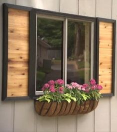 a window that has some flowers in it and is hanging on the side of a building