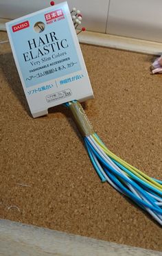 a pair of scissors sitting on top of a cork board next to some colorful wires