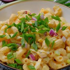 a bowl filled with macaroni salad and green onions