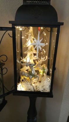 a lighted lantern with a christmas tree in the center and snowflakes on top