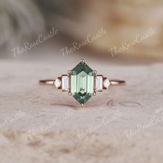 an emerald and diamond ring sitting on top of a rock