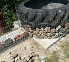 an outdoor hot tub surrounded by rocks and wire