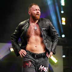 a shirtless man standing on stage with his hands in his pockets