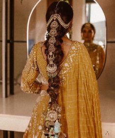 a woman with long hair in a yellow dress looking at her reflection in a mirror