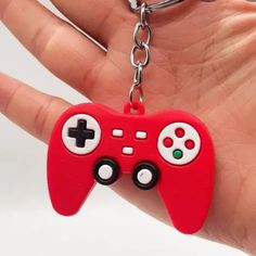 a red game controller keychain hanging from a person's hand