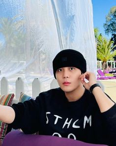 a young man sitting on top of a purple couch next to a white picket fence