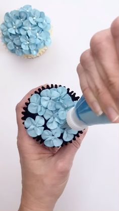 a person holding a cupcake with blue frosting on it