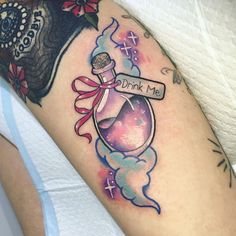 a woman's arm with a tattoo on it that reads drink me and has a bottle filled with liquid