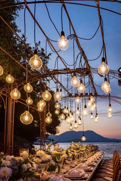 an outdoor dining area with lots of lights hanging from the ceiling and tables set for dinner