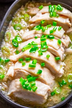 a pan filled with meat covered in green onions