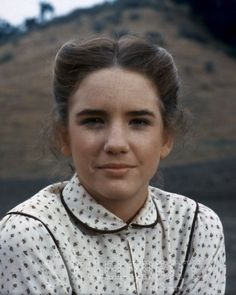 an old photo of a young woman wearing a white shirt and brown collared necktie